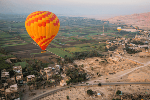 Colorful hot air balloon over scenic farmland.