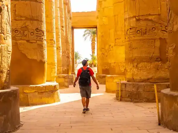 Person walking through ancient Egyptian temple columns.